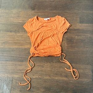 Crave Fame rust orange top with a mid riff cut out in size XS